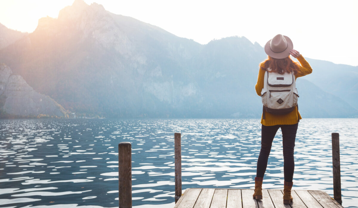 Mädchen steht an einem Steg am Traunsee mit Blick auf die Alpen
