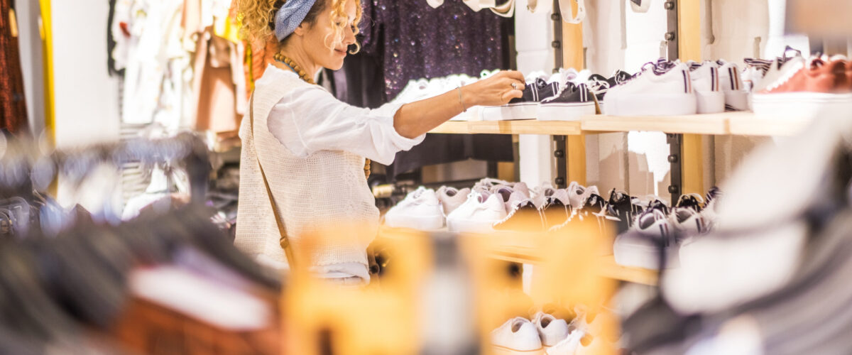 Eine sympathische, junge, kaukasische Frau kauft in einem Bekleidungs- und Schuhgeschäft in einem Einkaufszentrum der Stadt ein