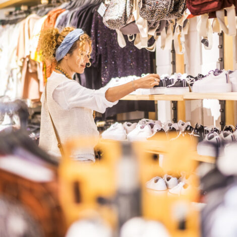 Eine sympathische, junge, kaukasische Frau kauft in einem Bekleidungs- und Schuhgeschäft in einem Einkaufszentrum der Stadt ein