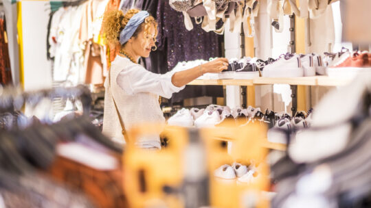 Eine sympathische, junge, kaukasische Frau kauft in einem Bekleidungs- und Schuhgeschäft in einem Einkaufszentrum der Stadt ein