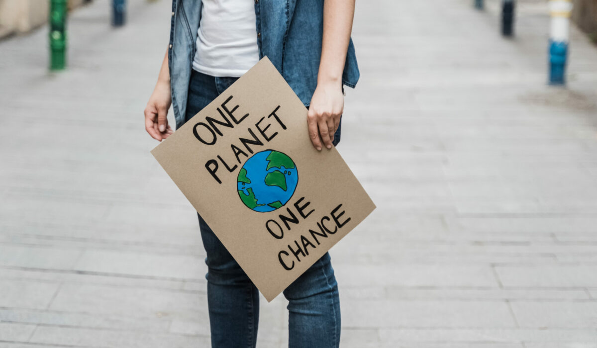 Frau hält Plakat "one planet, one chance" in der Hand
