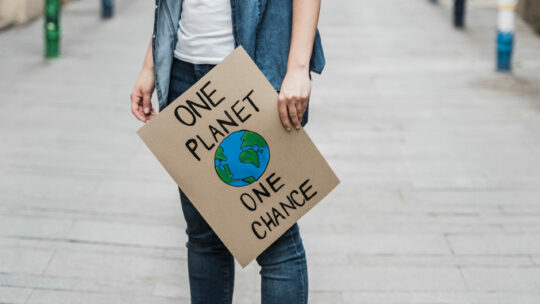 Frau hält Plakat "one planet, one chance" in der Hand