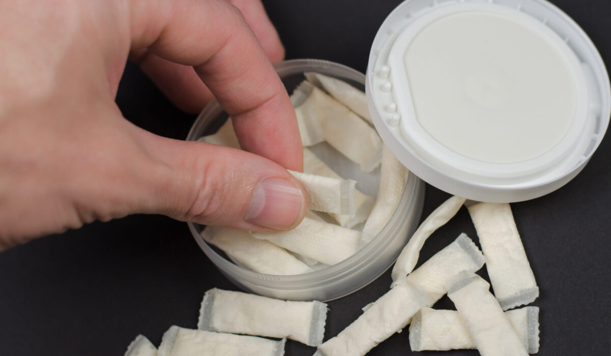 Hand nimmt Snus Beutel aus einer Dose.