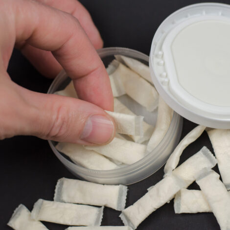 Hand nimmt Snus Beutel aus einer Dose.