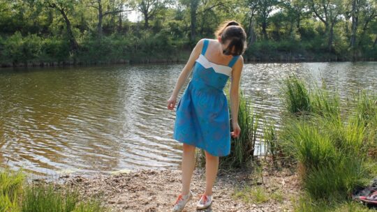 Stefanie mit einem blauen Sommerkleid am Fluss