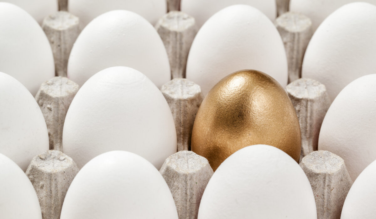 Ein goldenes Ei in Mitten von weißen Eiern in einem Eierkarton