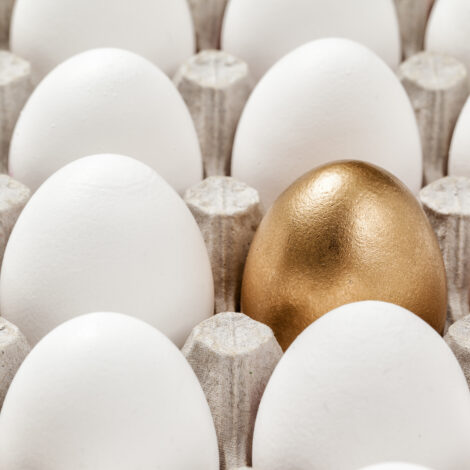 Ein goldenes Ei in Mitten von weißen Eiern in einem Eierkarton