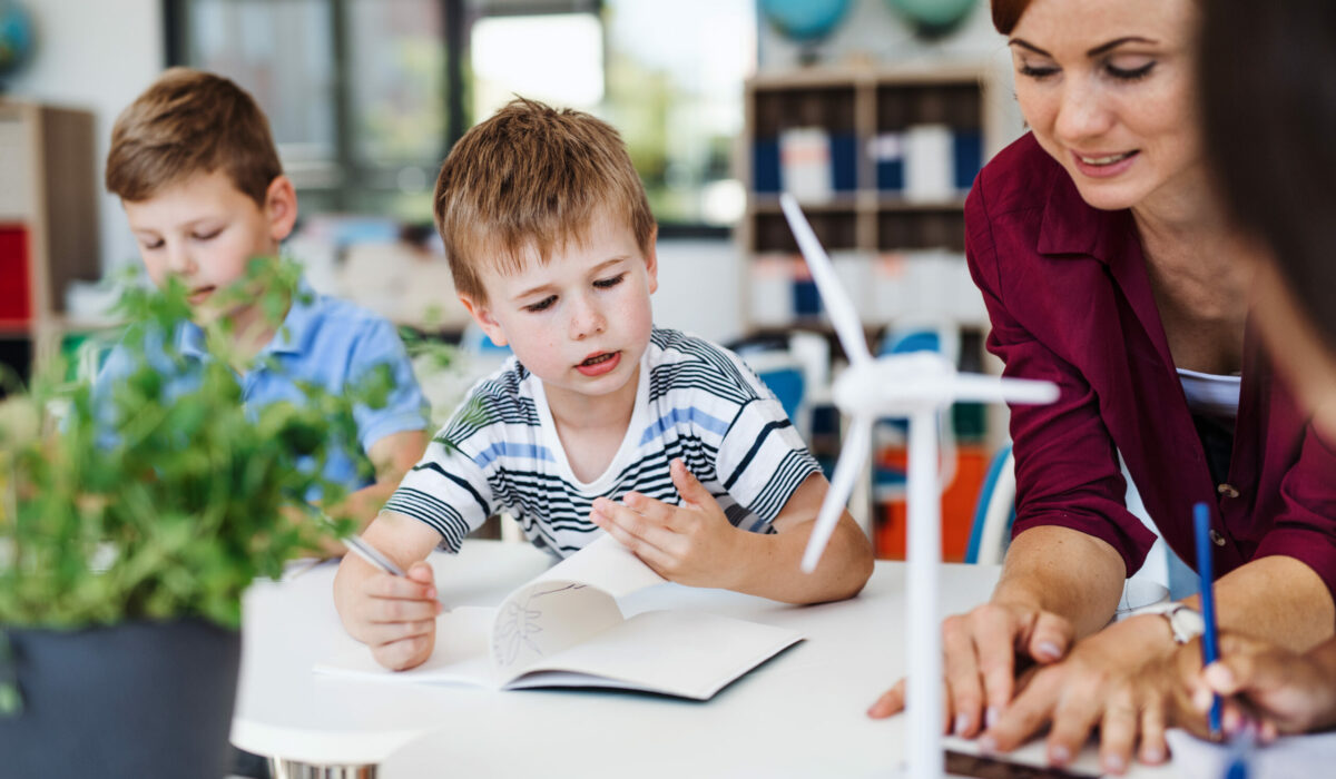 Gruppe von Schulkinder und Lehrerin reden über Windräder und Solarenergie