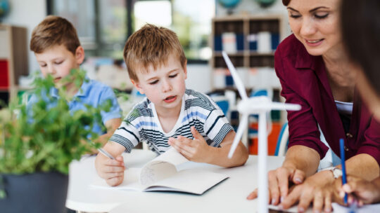 Gruppe von Schulkinder und Lehrerin reden über Windräder und Solarenergie