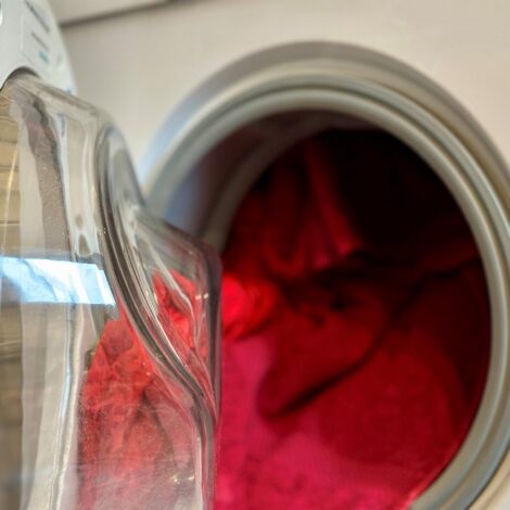 Offene Waschmaschine voll gefüllt mit bunten, roten Handtüchern und T-Shirts