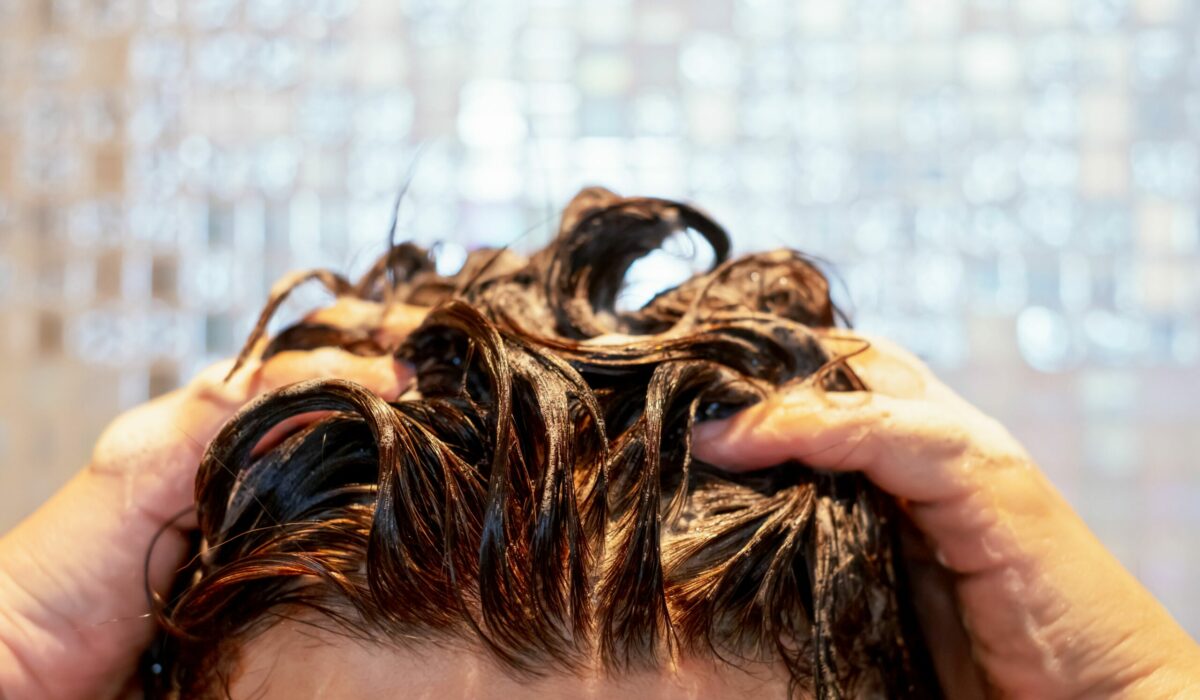 Frau wäscht sich die Haare unter der Dusche