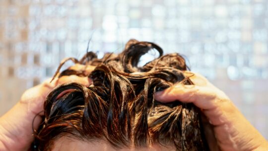 Frau wäscht sich die Haare unter der Dusche