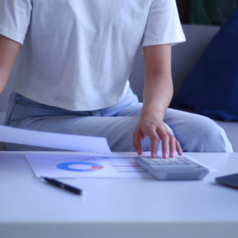 Junge Frauen arbeiten von zu Hause aus und analysieren Daten mit Taschenrechner und Laptop.