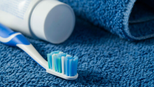 Zahnbürste und Zahnpaste auf blauem Handtuch